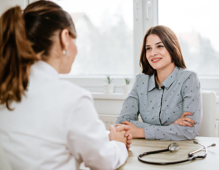 Paciente mulher conversando com a médica em um consultório durante uma consulta.