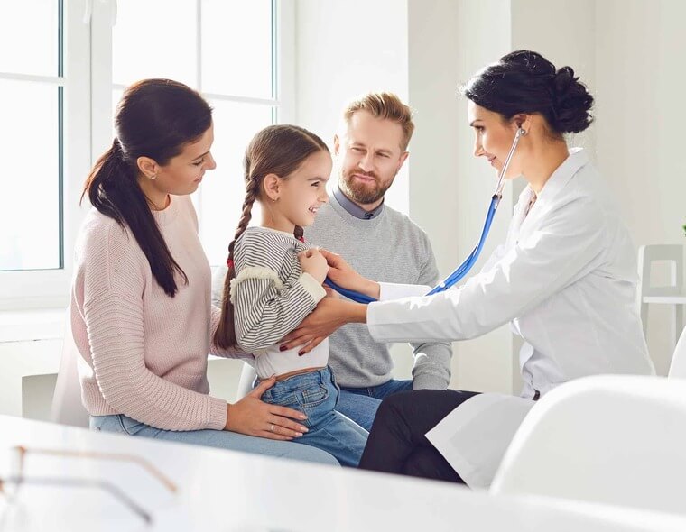 Uma médica examinando uma paciente criança que está acompanhada de seus pais.