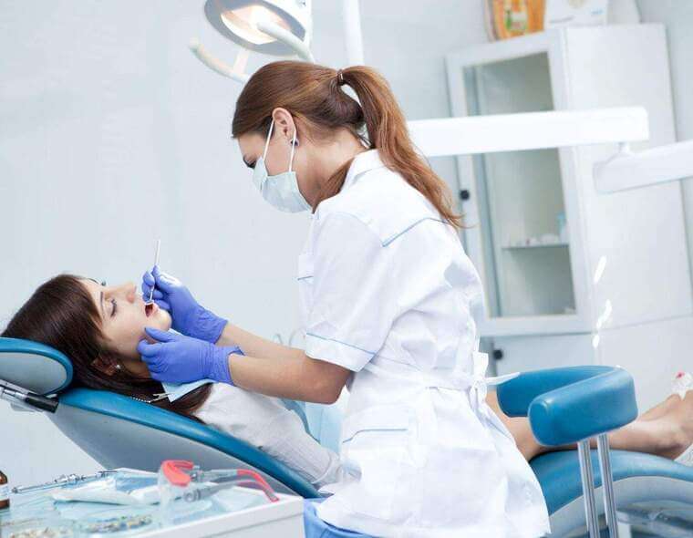 Mulher sendo atendida por uma dentista