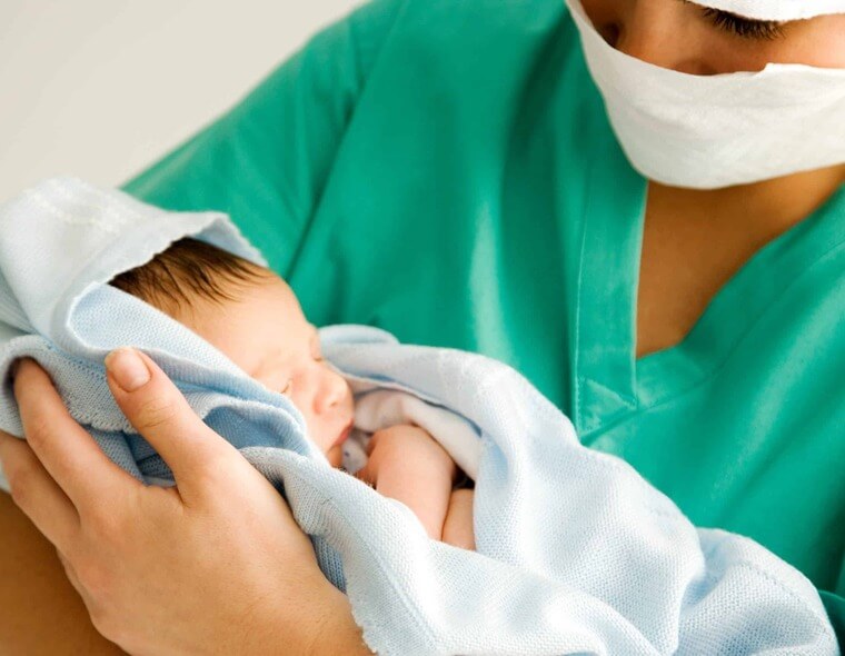 Médica segurando um recém nascido no hospital e maternidade.