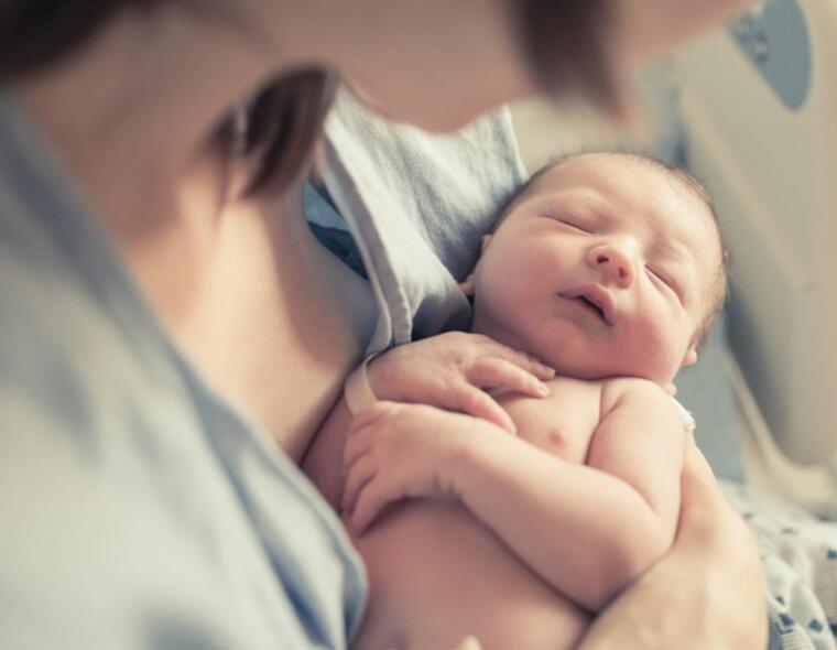 Bebê recém-nascido descansando nos braços da mãe na maternidade.