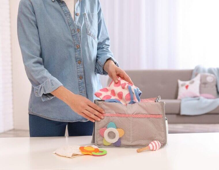 Uma mulher colocando em uma bolsa o que levar para a maternidade.