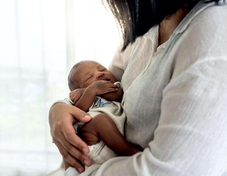 Mãe segurando o seu filho recém-nascido no colo - Quanto custa um parto particular?.